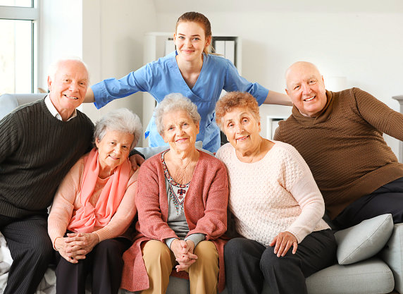 Young caregiver with group of elderly smiling.