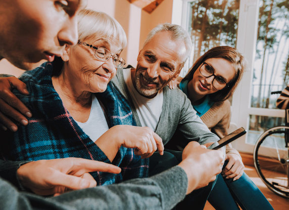 Caretakers looking at elderly woman smiling.