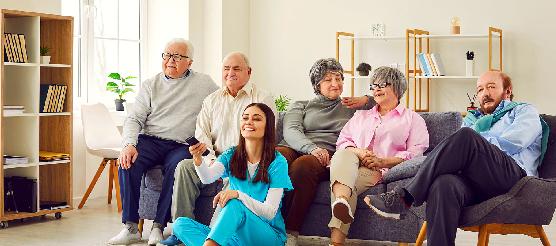 Female nurse with group of elderly watching TV.