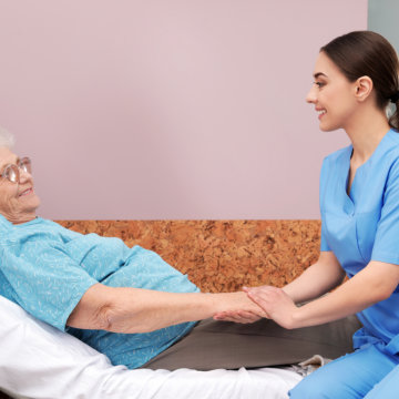 Elderly woman lying in bed with nurse.