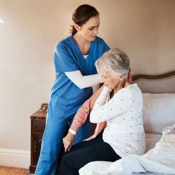 Nurse helps woman to dress.