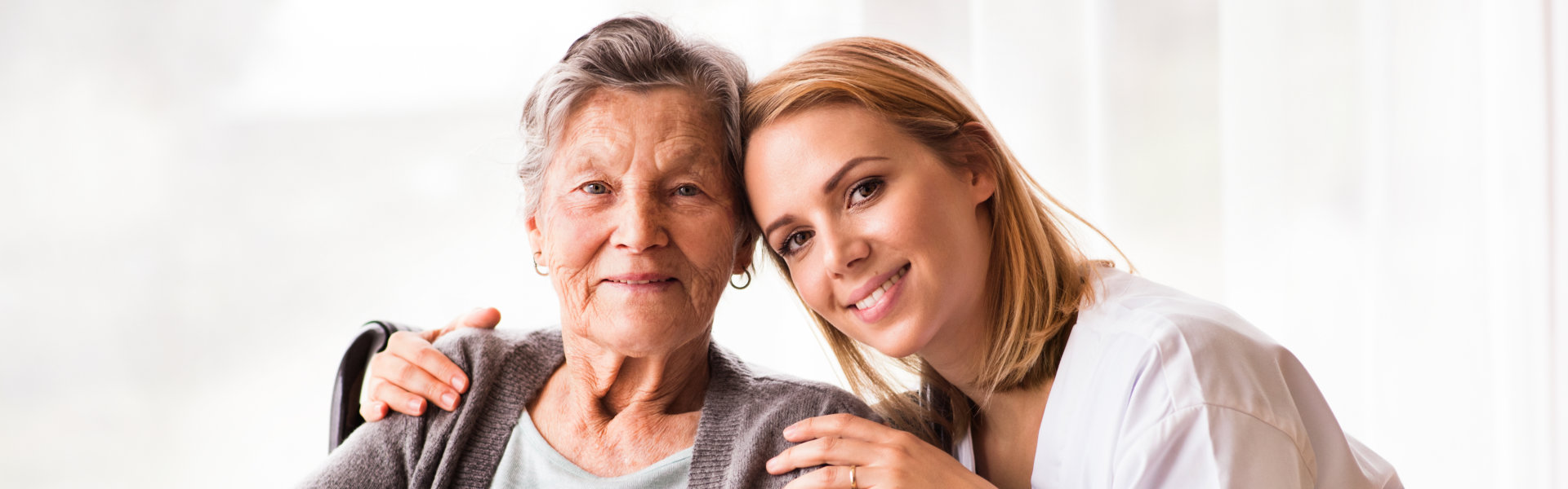 Woman in wheelchair with nurse smiling.