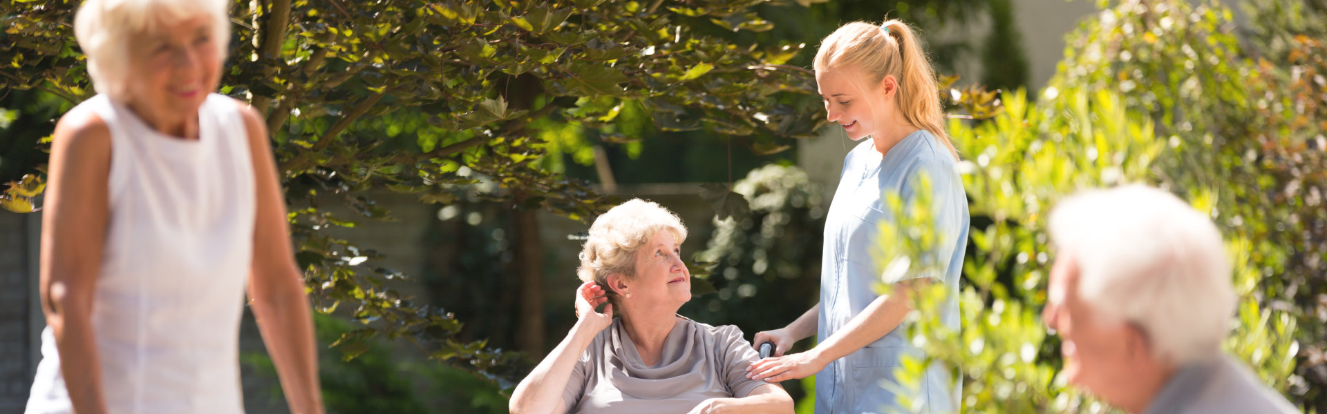 Woman in wheelchair with her nurse outside.